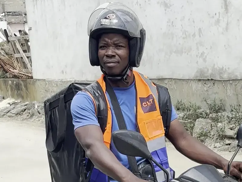 Un livreur CLT à moto, gilet et casque